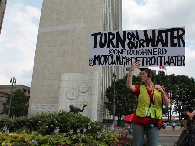 A demonstrator holds a sign during a rally against Detroit's water shut-offs on July 18, 2014.