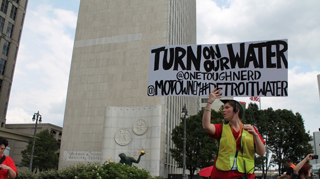 A demonstrator holds a sign during a rally against Detroit's water shut-offs on July 18, 2014.