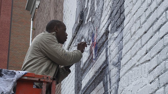 Tylonn J. Sawyer puts the finishing touches on a mural dedicated to Detroit Lions player Reggie Bush late last year.