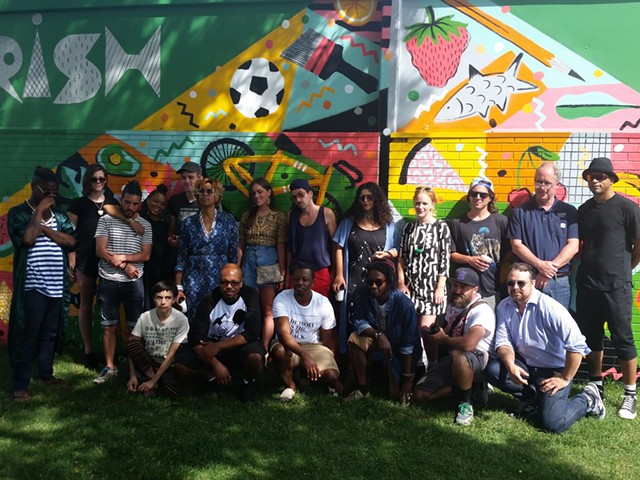 Selected artists, Eastern Market President Dan Carmody, and Festival Producer Roula David stand in front of the year's first mural,  created by artists Jesse Kassel and Ellen Rutt.