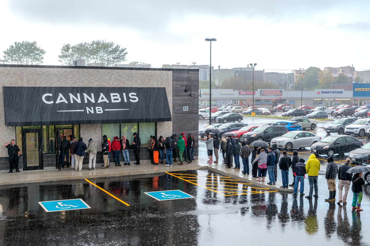 People waiting in pouring rain to purchase cannabis legally from a Cannabis NB store on the first day of legalization in Canada.