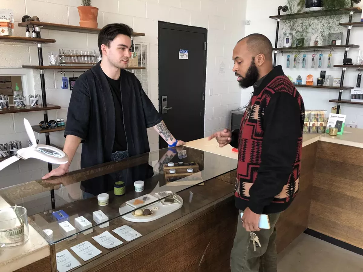 Image: A budtender helps a customer at Detroit’s BotaniQ.