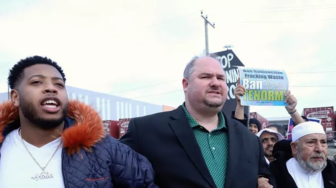 State Rep. Isaac Robinson (center) locks arms with state Rep. Jewell Jones (left) and Imam Salah Algahim (right) as they march from a nearby school to protest US Ecology on Detroit's east side.