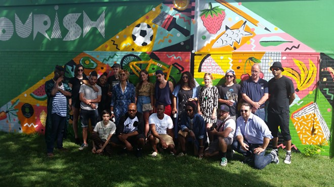 Selected artists, Eastern Market President Dan Carmody, and Festival Producer Roula David stand in front of the year's first mural,  created by artists Jesse Kassel and Ellen Rutt.