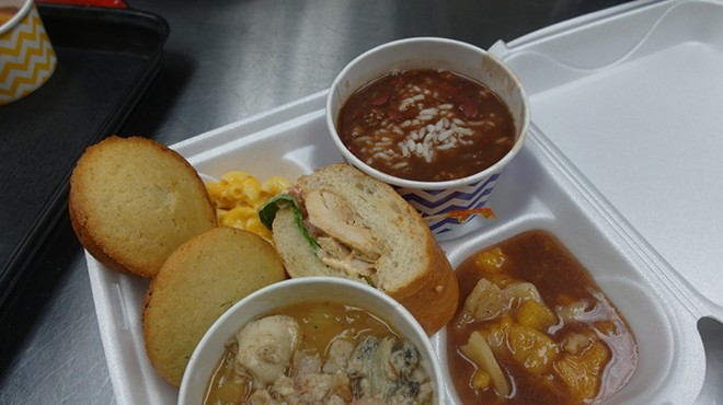 Front, the premium seafood gumbo, Poor Boy sandwich center, cornbread and mac 'n cheese left, peach cobbler right, and red beans and rice back.