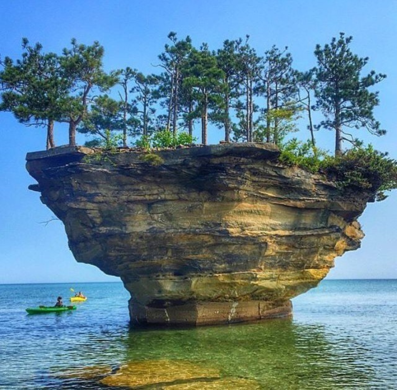 Turnip Rock, Port Austin
Located at the shores of Lake Huron in Port Austin, this beautiful large stone gets its shape from becoming separated from the main land from water erosion and you can only get there by boat and kayaks. On top of this rock, there are very large 20&#146; high trees.  (Photo via Turnip Rock official travel page)