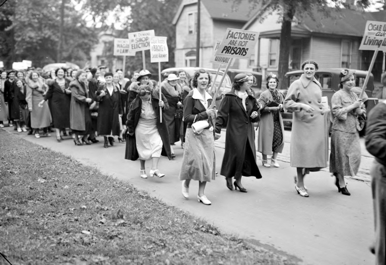 1930s | Large group of women, identified as Cigar Girls, march with picket signs, reading, "Factories are not prisons" and "We demand shop elections," at unidentified location in Detroit, Michigan. "Sitdowning became a popular tactic among disgruntled workers, especially among the predominately female work force of Detroit's tobacco companies," from Up in smoke: Cigar making in Detroit by Thomas L. Jones, special to The Detroit News.