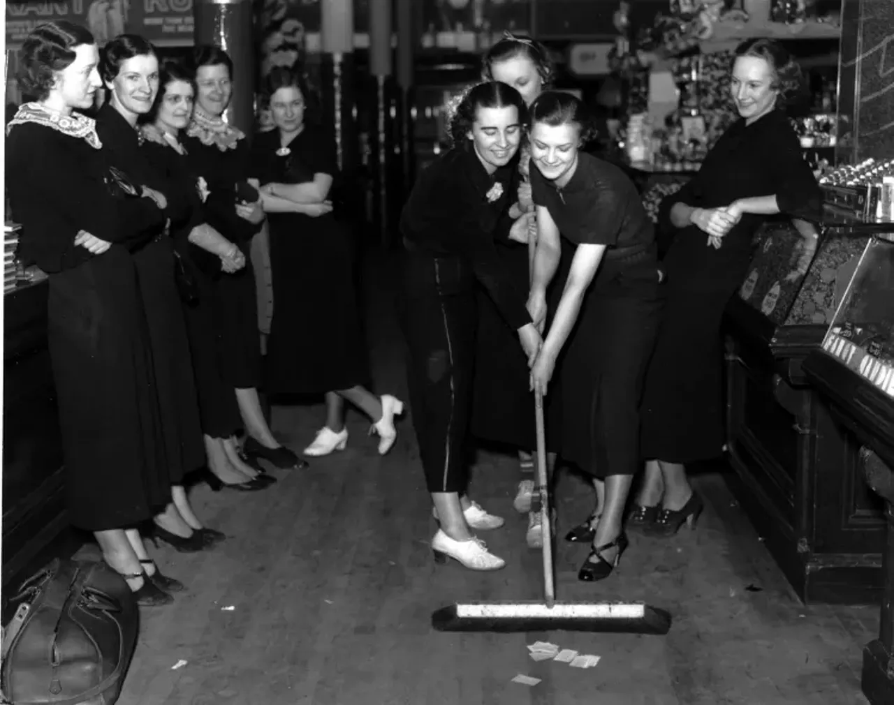 1930s | Two women push broom while others watch at Woolworth department store in Detroit, Michigan during sit-down strike.