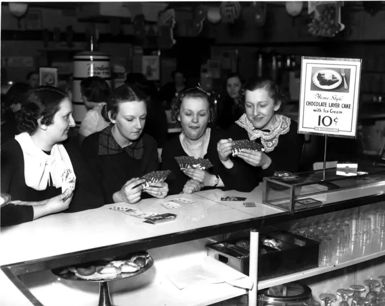 1930s | Four women play cards sitting at lunch counter at Woolworth department store in Detroit, Michigan during sit-down strike.
