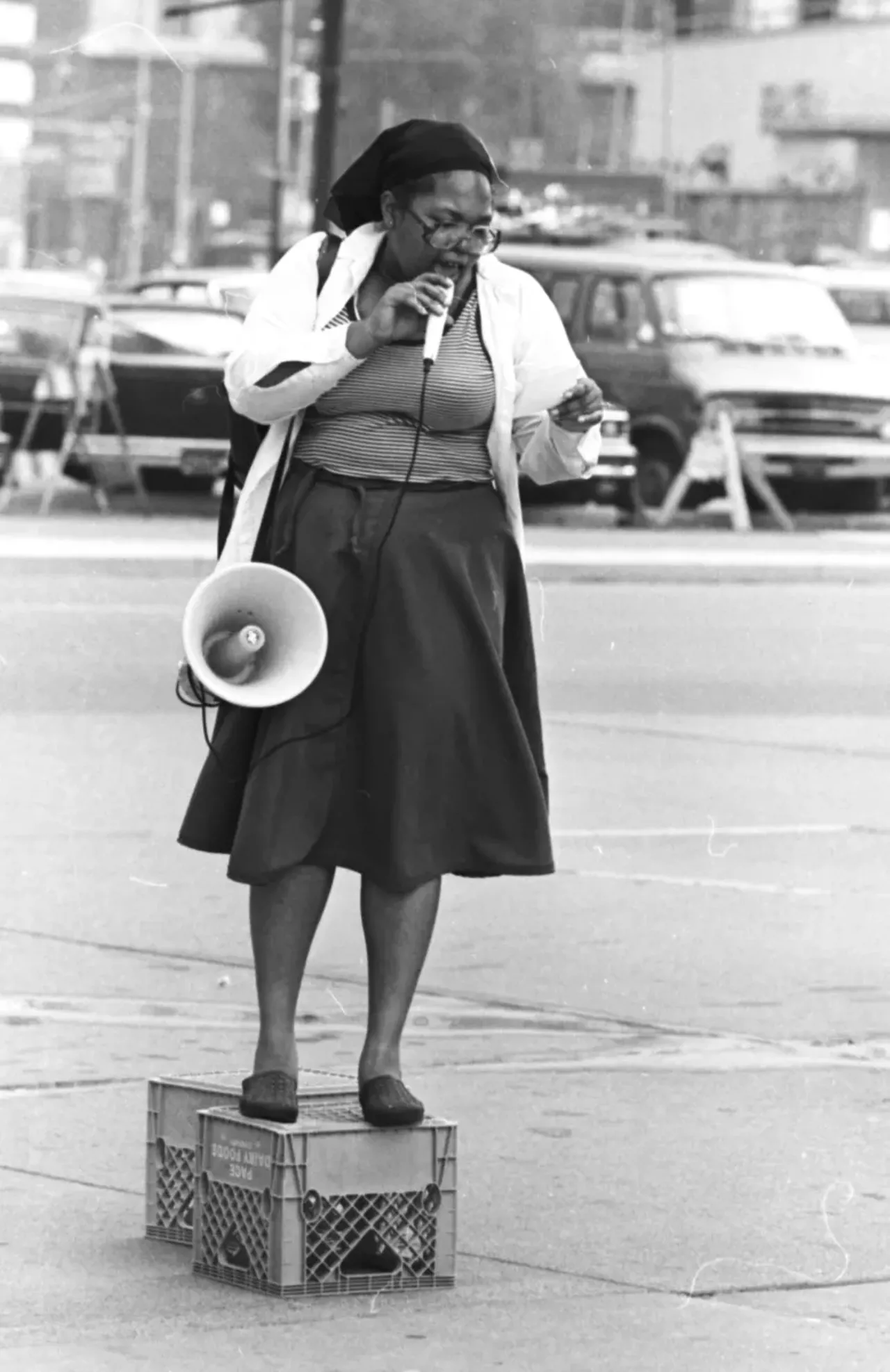 1980s | African American woman stands on a crate and speaks into a microphone attached to a bull horn at the City-County Building at a picket against KKK & Nazi Groups