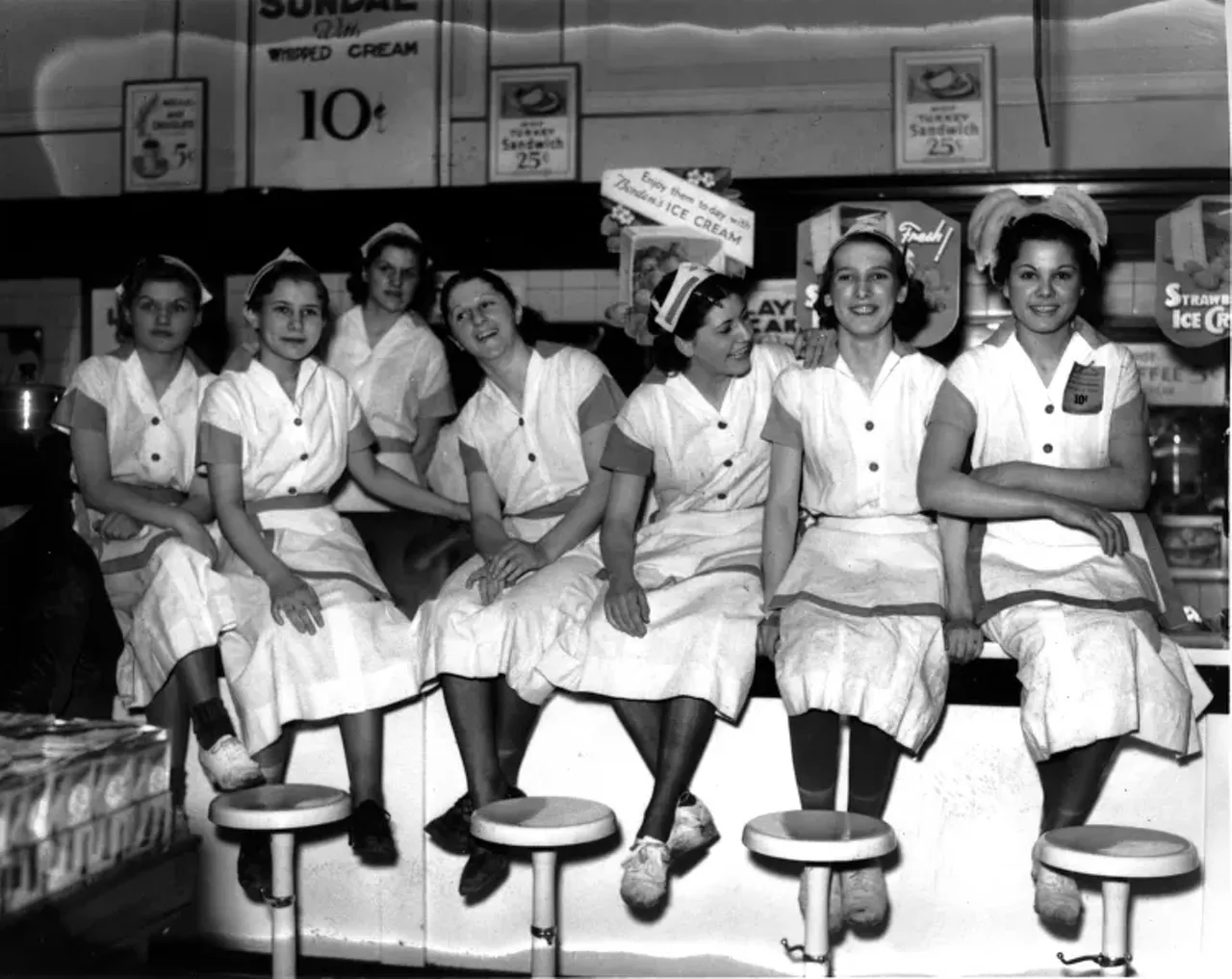 1930s | Uniformed waitresses sit on lunch counter at Woolworth department store in Detroit, Michigan during sit-down strike.