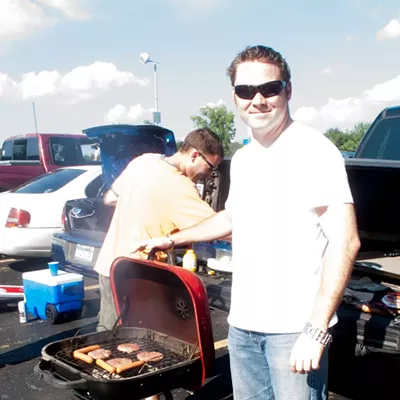 Rich Tideswell prepares a burger while Rob Grieser proudly shows off his grill.