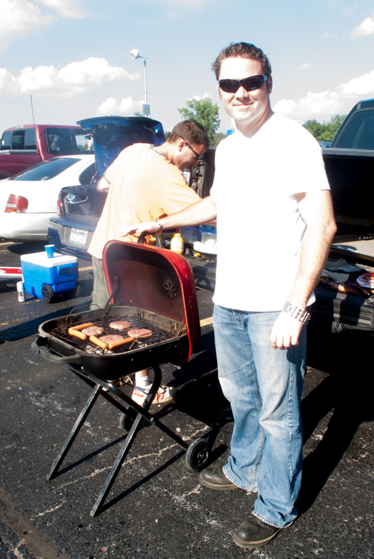 Rich Tideswell prepares a burger while Rob Grieser proudly shows off his grill.