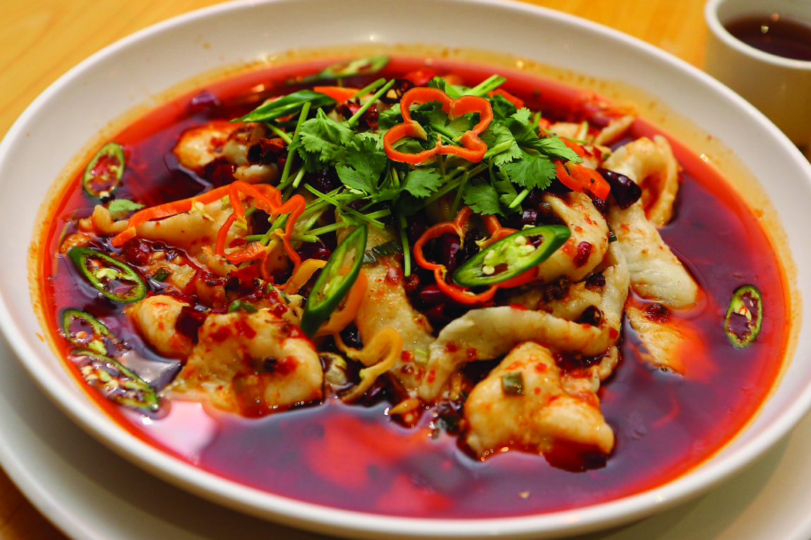 Szechuan boiled fish, featuring golden whitefish in crimson sauce sprinkled with green cilantro stems, and pungent tiny black berries, from Empire Dynasty in Farmington Hills.