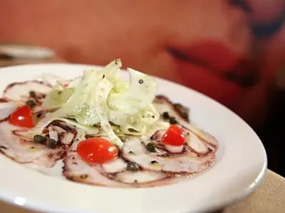 Carpaccio di Polipo, thinly sliced octopus, fennel, celery, grape tomatoes, capers, lemon, extra-virgin olive oil, front, with mural, back, from Bella Piatti in Birmingham.