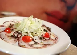 Carpaccio di Polipo, thinly sliced octopus, fennel, celery, grape tomatoes, capers, lemon, extra-virgin olive oil, front, with mural, back, from Bella Piatti in Birmingham.