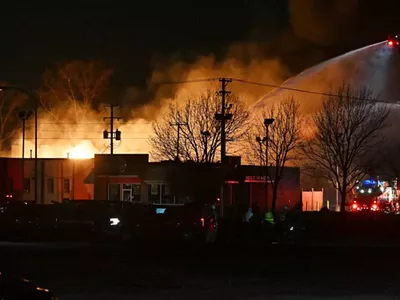 Fire departments battle an industrial fire near 15 Mile Road and Groesbeck Highway in Clinton Township on Monday.