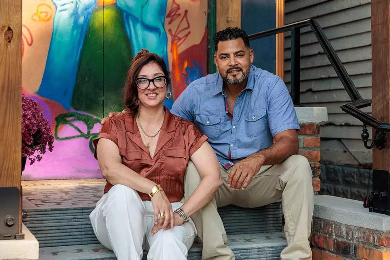 Tanya Saldivar-Ali and Luis Ali sit on the front porch of the fully renovated historic house that now serves as a resource center for local contractors in Detroit.