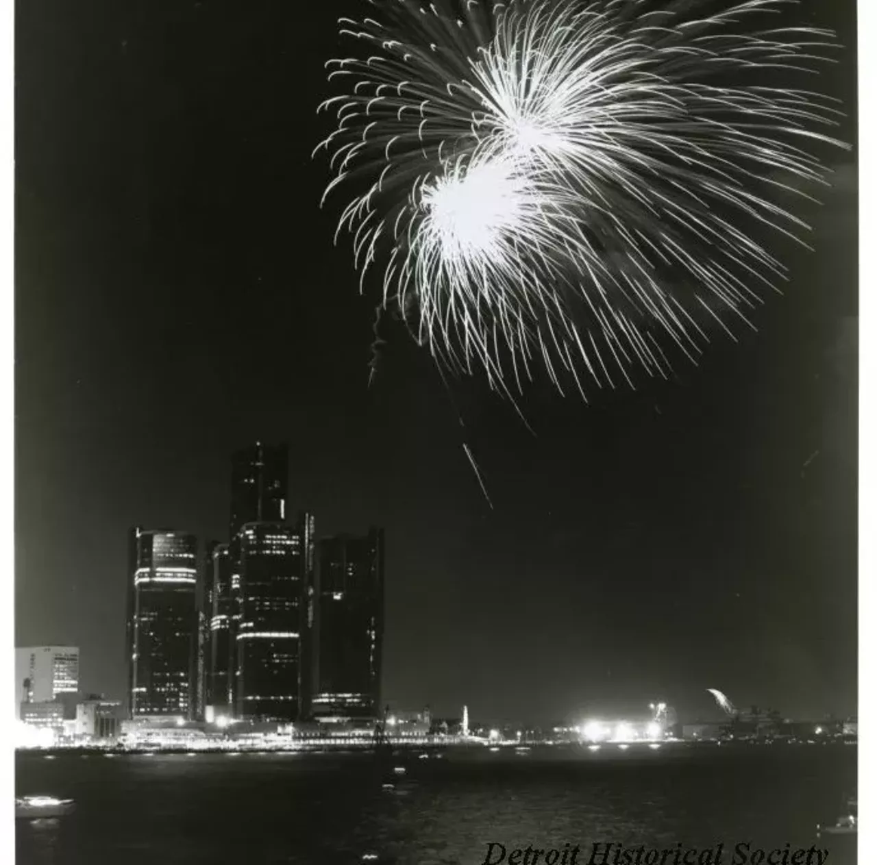 "Black and white photographic print depicting a fireworks display over the Detroit River at night, with the Renaissance Center and Blue Cross Blue Shield Building in the background. Caption #1 reads- The Hudson's-Stroh's fireworks extravaganza will again be the "crowning jewel" in the events planned for the Detroit-Windsor International Freedom Festival, June 30 - July 4. This year's fireworks display will begin downtown at dusk on June 30 and will conclude after several tons of colorful starbursts have been shot into the night sky from barges on the Detroit River. In case of bad weather, everything will be rescheduled for July 1. The fireworks is only one of over 75 Festival events. Caption #2 reads- For release on or after Tuesday, June 5, 1979. Detroit River "lights up" June 29 - For the 21st consecutive year, the spectacular Freedom Festival Fireworks will herald the opening of Detroit and Windsor's annual celebration. This year's fireworks display will begin at 9:55 p.m., Friday, June 29, from barges anchored midway in the Detroit River opposite the Veterans Memorial Building, Cobo Hall and Ford Auditorium. More than 600,000 people are expected to watch the seven tons of colorful starbursts light up the skylines of the two cities. In case of bad weather, everything will be rescheduled for Saturday, June 30."