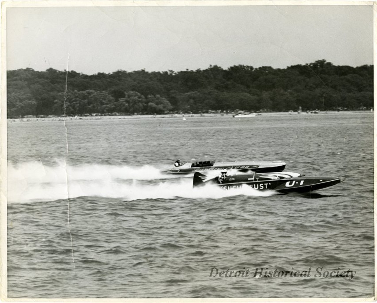 "Black and white photo of MISS PEPSI (U-99) background, and SUCH CRUST (U-1) foreground, racing on the Detroit River. The Belle Isle shoreline can be seen in the background. On the verso is the name Ray Moore and the notation - "start of 2nd heat." The back of the photo is also marked "Detroit Times, July 4, 1949." The Detroit Memorial Race was held on July 4th in 1949."