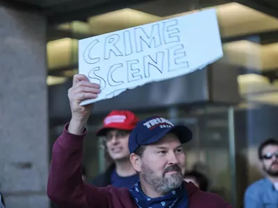 A Trump supporter wielding a sign alleging voter fraud outside of Detroit's TCF Center.
