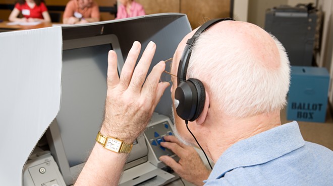 A man uses a touch screen voting machine equipped for the hearing and vision impaired.