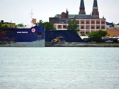 Mounds of petcoke sit unprotected along the bank of the Detroit River waiting for transport.