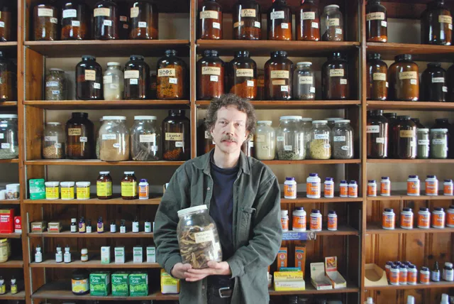 Gary Wanttaja stands before his jars of herbs.