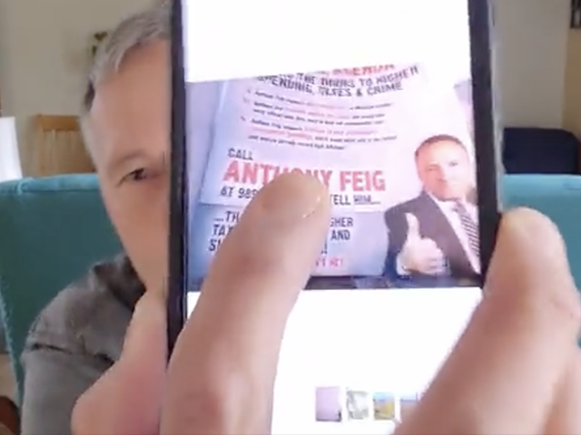 Anthony Feig, a Democrat running for state House, shows a political ad from his opponents that featured his cellphone number.