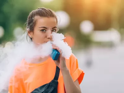 A young woman vaping nicotine.