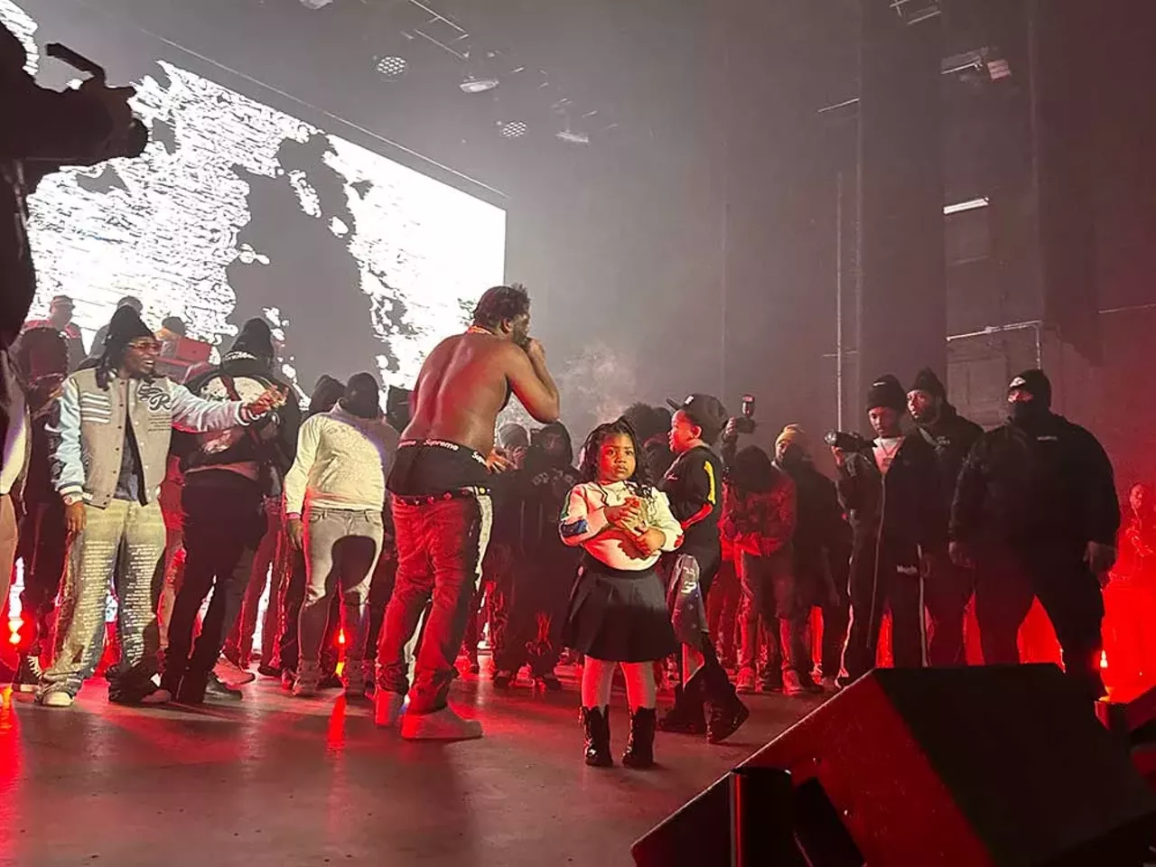 Flint rapper YN Jay records Rio Da Yung Og, whose daughter holds a stack of cash on stage.