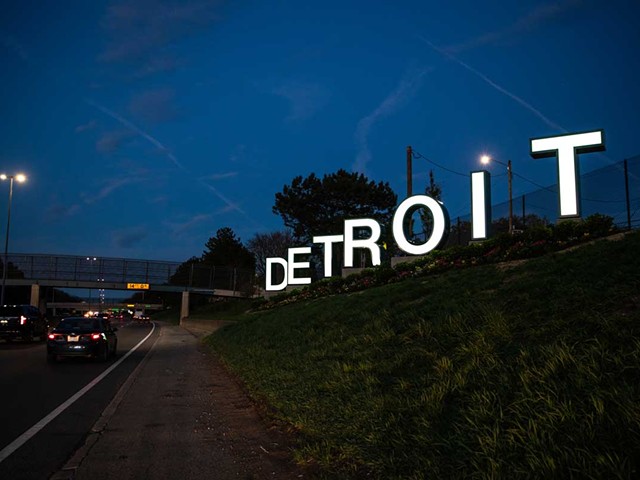 The large Detroit sign illuminated at night.
