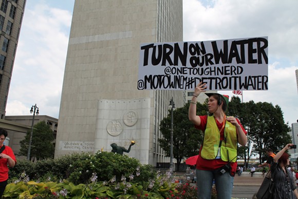 A demonstrator holds a sign during a rally against Detroit's water shut-offs on July 18, 2014. - Ryan Felton/Metro Times