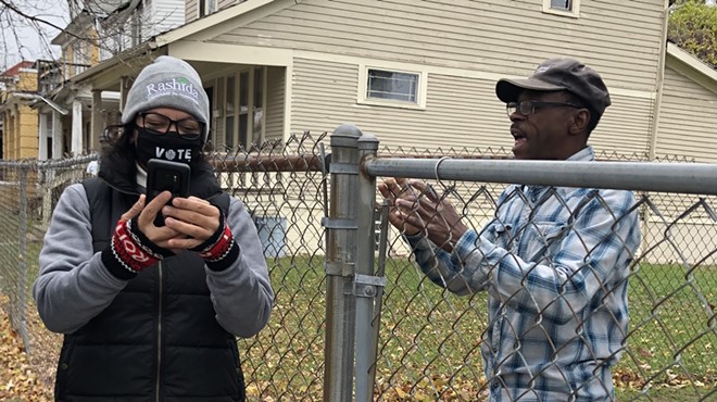 Rashida Tlaib helps one of her constituents navigate the unemployment system while knocking on doors on Sunday.