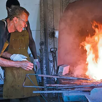 Carl Nielbock and his assistant heat metal at Fort Wayne’s 1846 blacksmithing shop.