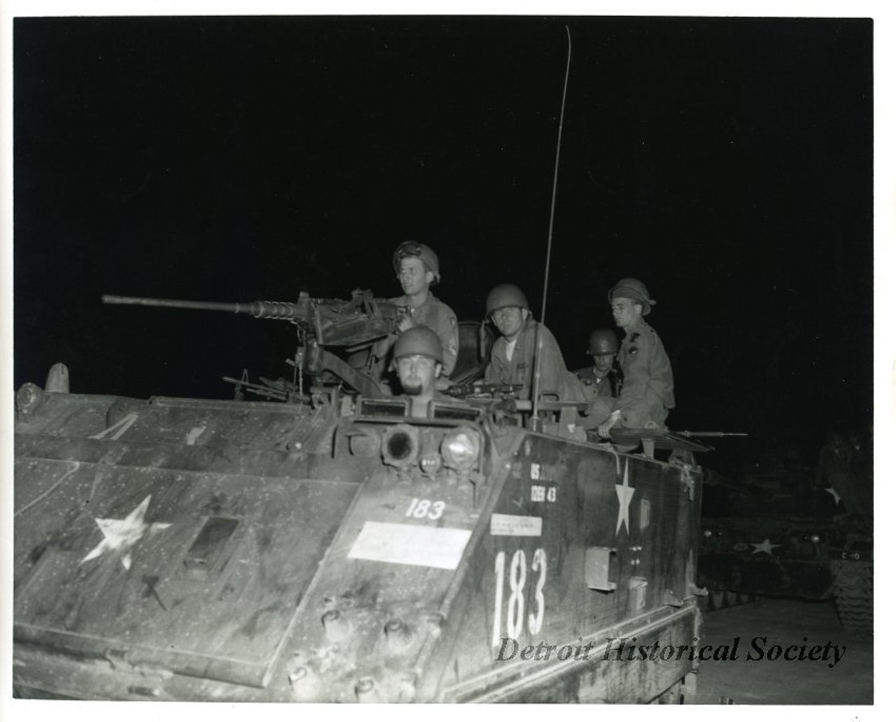 "One black and white photograph of a group of Michigan National Guardsmen who are on patrol during the 1967 Detroit Riot. The nighttime photo shows an armored personnel carrier (#183) with a machine gun and five guardsmen."