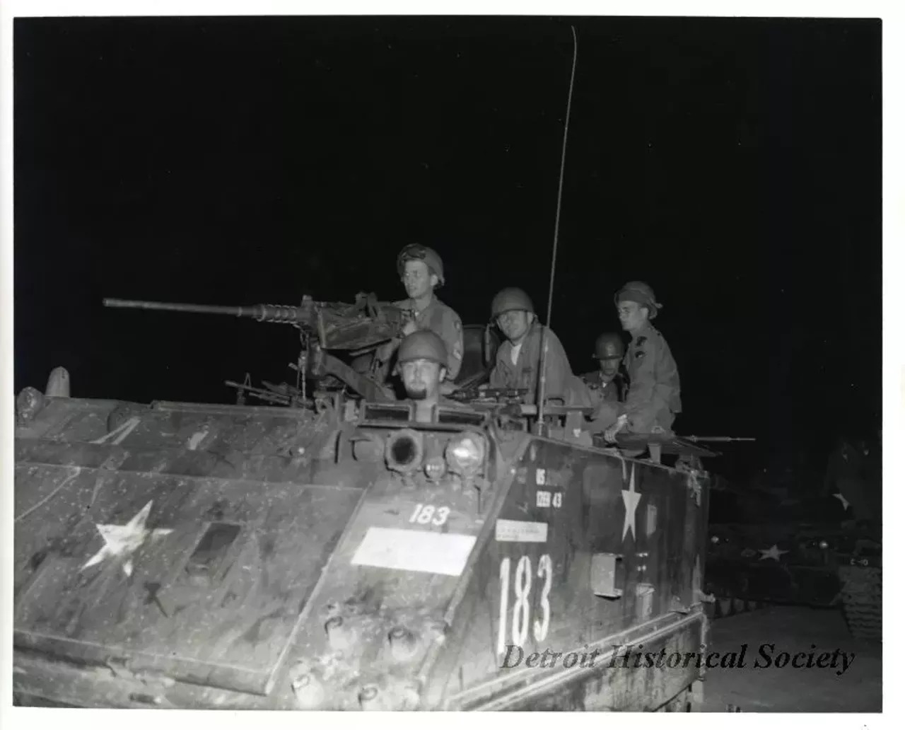 "One black and white photograph of a group of Michigan National Guardsmen who are on patrol during the 1967 Detroit Riot. The nighttime photo shows an armored personnel carrier (#183) with a machine gun and five guardsmen."