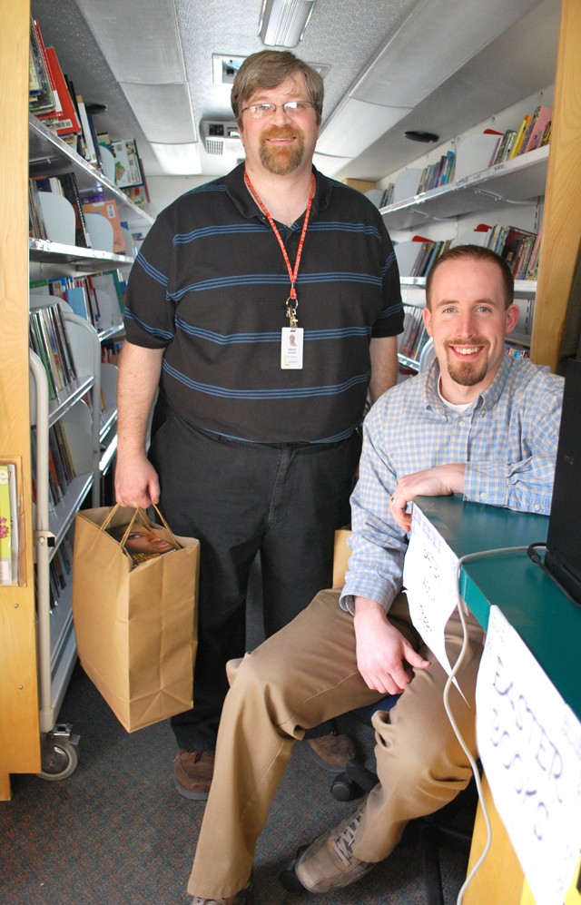 Ryan Boyd, right, and Aaron Jacobsen with his bags full of books inside the bookmobile. - Photo: Detroitblogger John