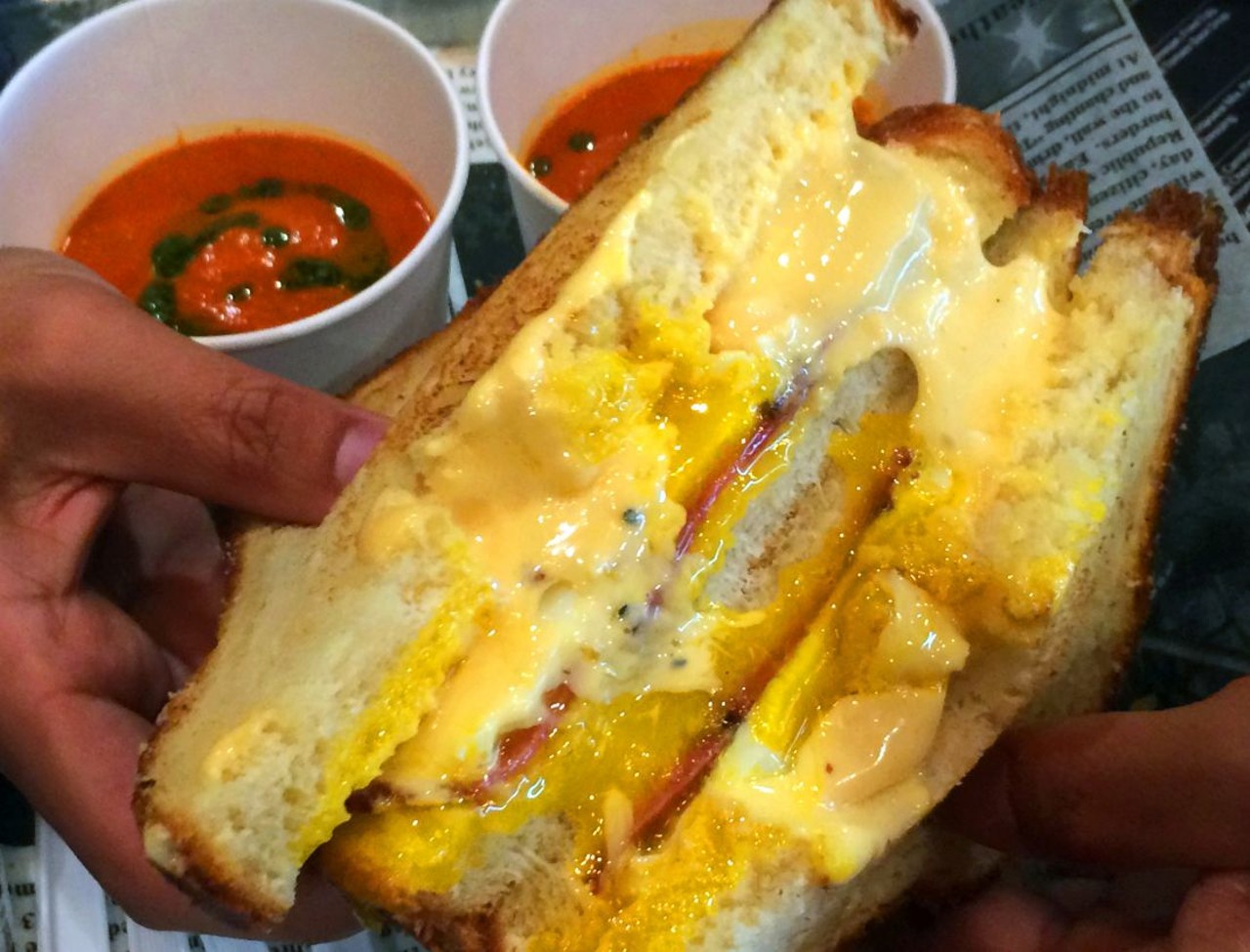 "All Up In Your Grill&#148; Cheese Sandwich with a fried egg, turkey bacon, cheese fondue, smoked gouda fondue, and parmesan next to a roasted tomato basil soup