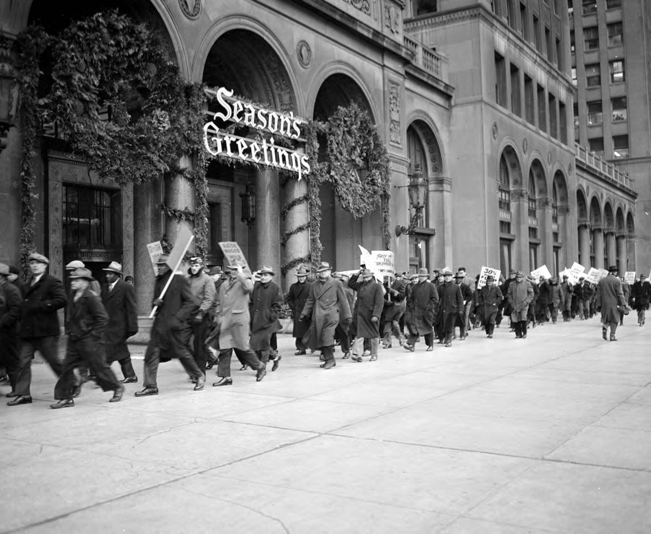 
Dec. 10, 1945: In Detroit, striking UAW members, carrying windblown signs, hunch into their overcoats as they picket in front of the General Motors Building, which is decorated for Christmas.
