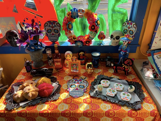 An ofrenda is an altar decorated with offerings to the dead like marigolds, food, photos of the deceased, sugar skulls, and Pan de Muerto (day of the dead bread).