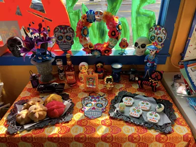 An ofrenda is an altar decorated with offerings to the dead like marigolds, food, photos of the deceased, sugar skulls, and Pan de Muerto (day of the dead bread).