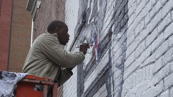 Tylonn J. Sawyer puts the finishing touches on a mural dedicated to Detroit Lions player Reggie Bush late last year. - Andrew Erdmans