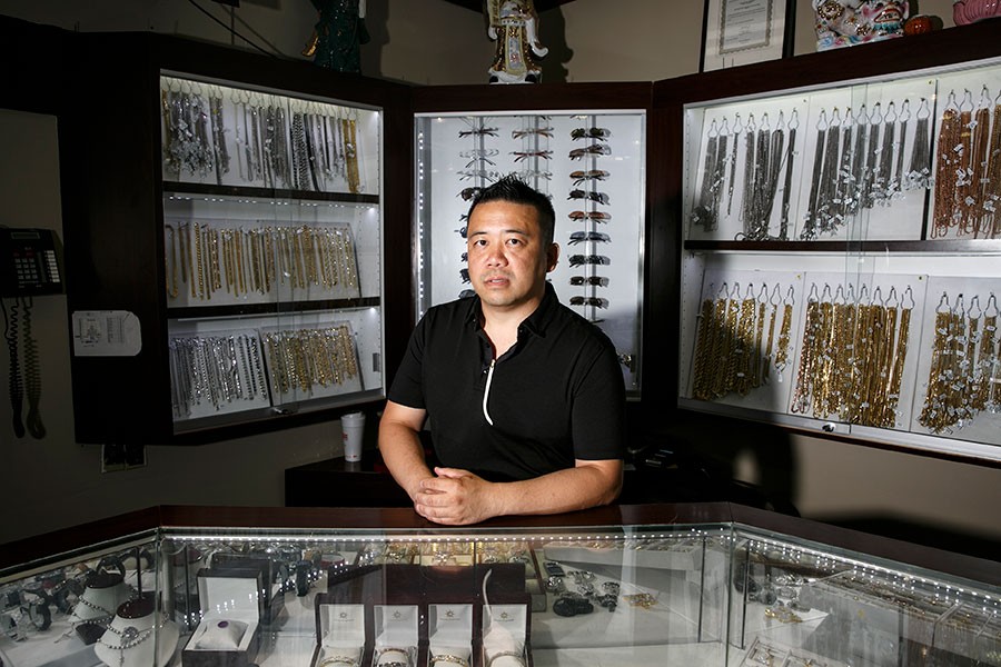 Gary Yee, manager of Golden Sun Jewelry, stands in front of some of the Cartier sunglasses he sells. - Sean Proctor