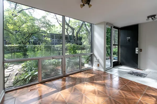 The entry way to this Mies van der Rohe townhouse features floor to ceiling windows for plenty of natural lighting. - Courtesy of O'Connor Real Estate