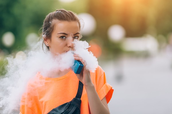 A young woman vaping nicotine. - Shutterstock