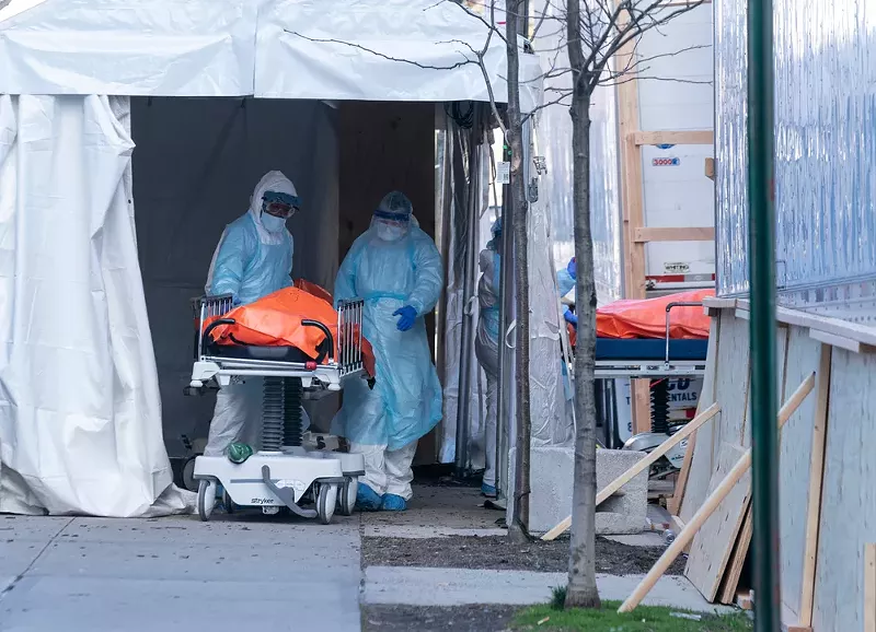 Body of deceased patient in orange bag moved from hospital to refrigerator truck serving as temporary morgue outside of Wyckoff Heights Medical Center in Brooklyn. - Shutterstock.com