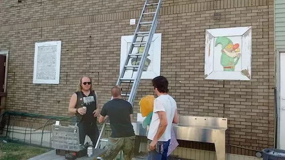 Lampinen (left) and Easter (right) get ready to adorn a wall with more art. - Photo by Michael Jackman