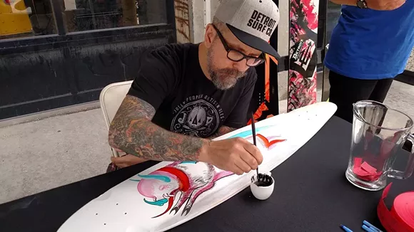 Jolly Pumpkin beer label artist Adam Forman begins work on a custom-painted Detroit Surf Co. longboard-style skateboard, creatively blending together Jolly Pumpkin beer labels with a pig/bat design on a custom-painted Detroit Surf Co. longboard, allowing patrons a rare chance to see the beer label artist in action. - Courtesy of Jolly Pumpkin