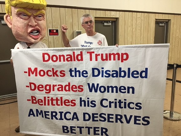 The Bernie Sanders event in Dearborn is warming up with Tom Moran, 61, a retired bus driver from Fenton, MI. He's been traveling the country protesting Trump. - Photo by Colin Maloney.